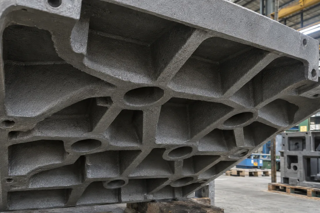 Underside of a grey iron machine base casting showing stiffening ribs